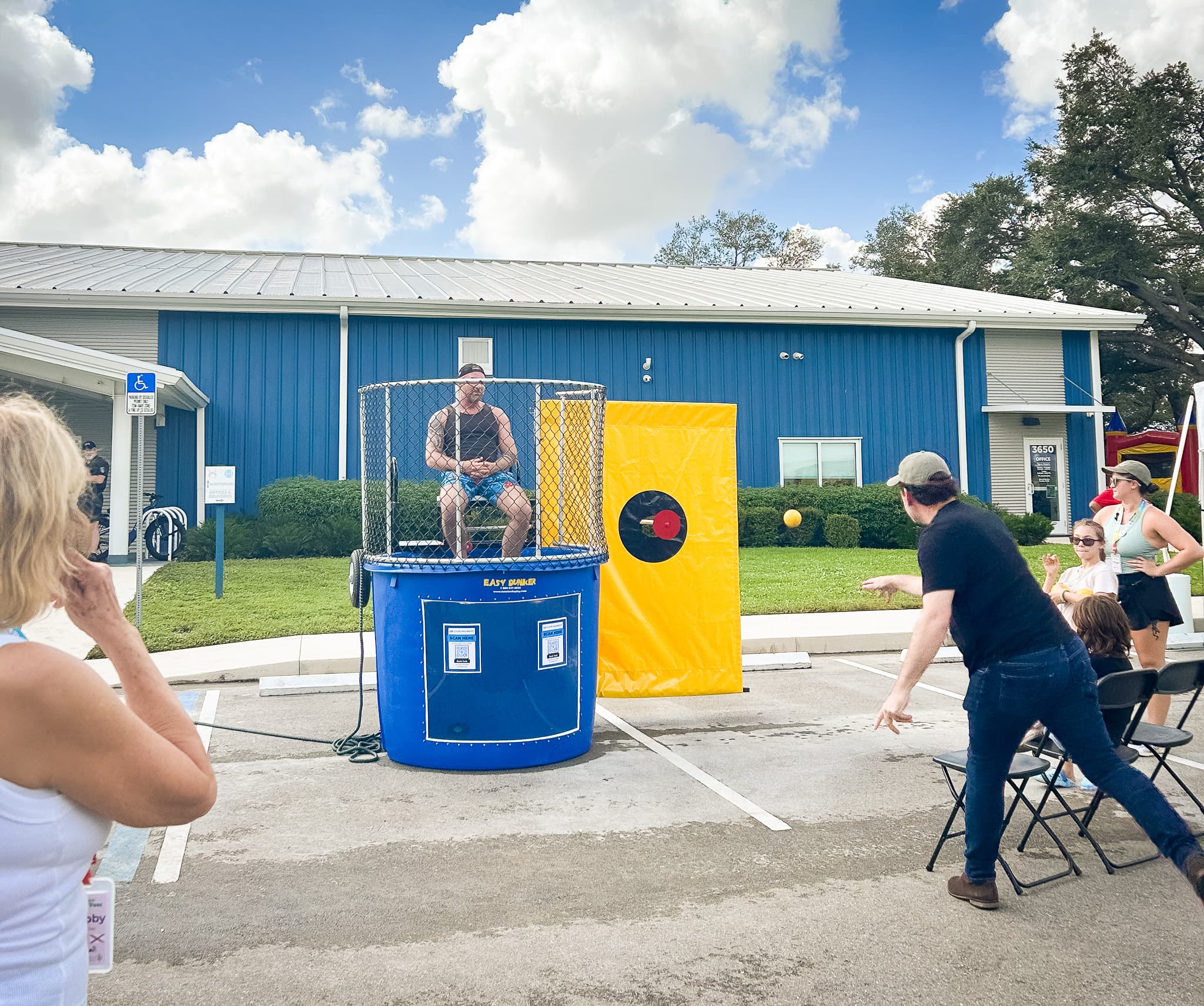 Group of people gather around dunk tank with Pastor Dan Minor pitching