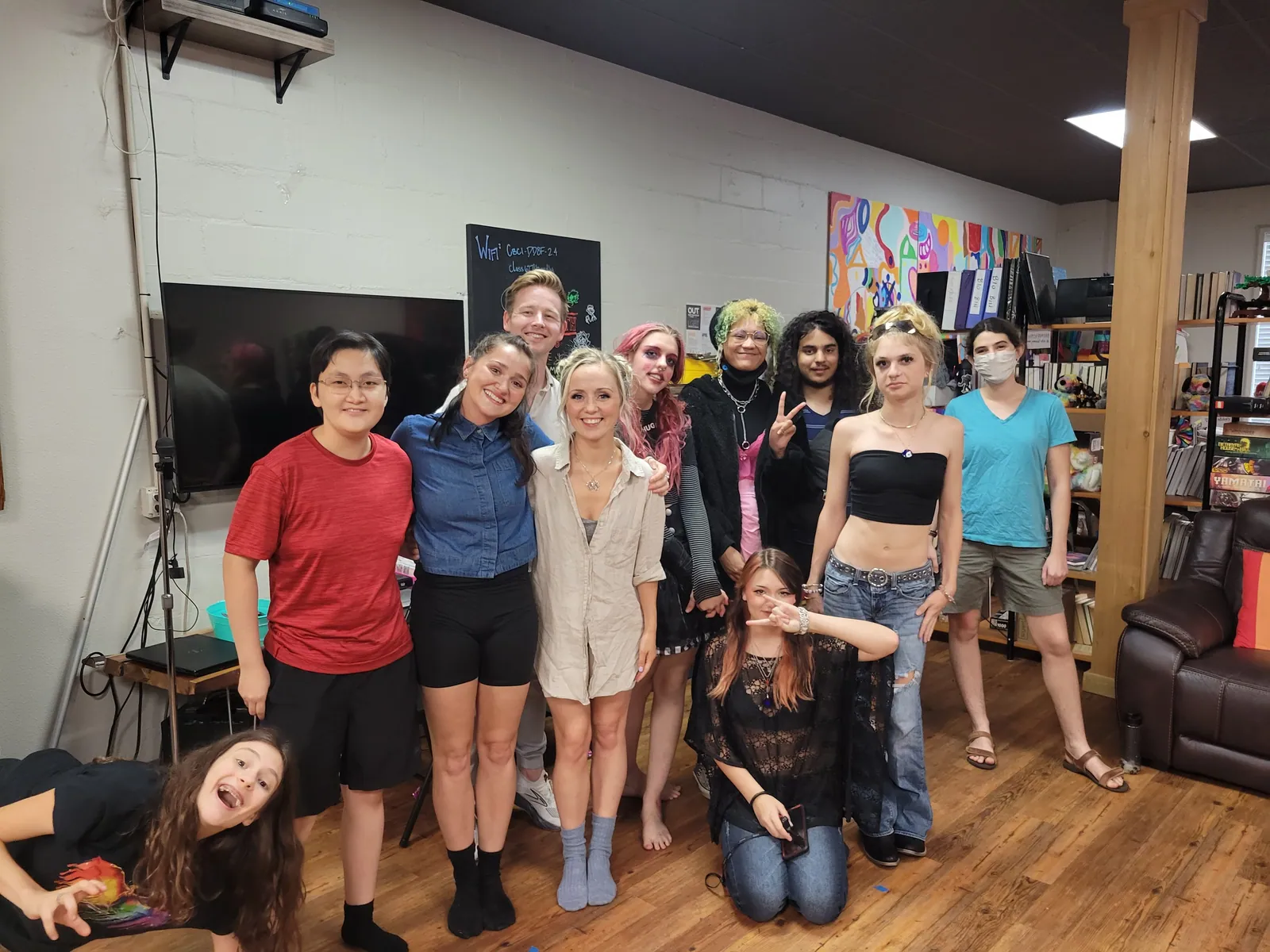 About a dozen young people posing together in a room at the center, one lying on the floor in front.