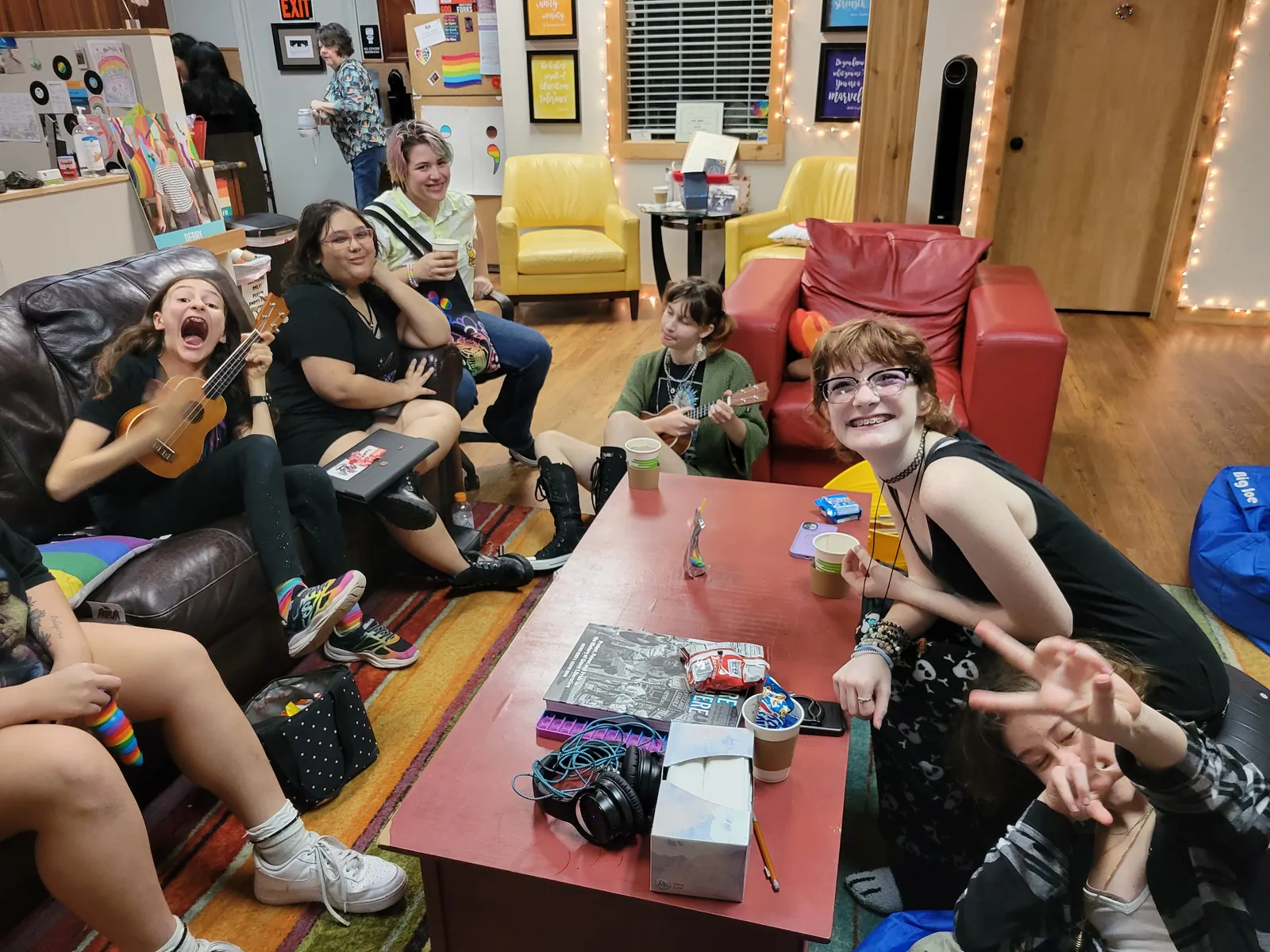 Young people laughing and relaxing on couches in the lounge, one playing a ukulele.