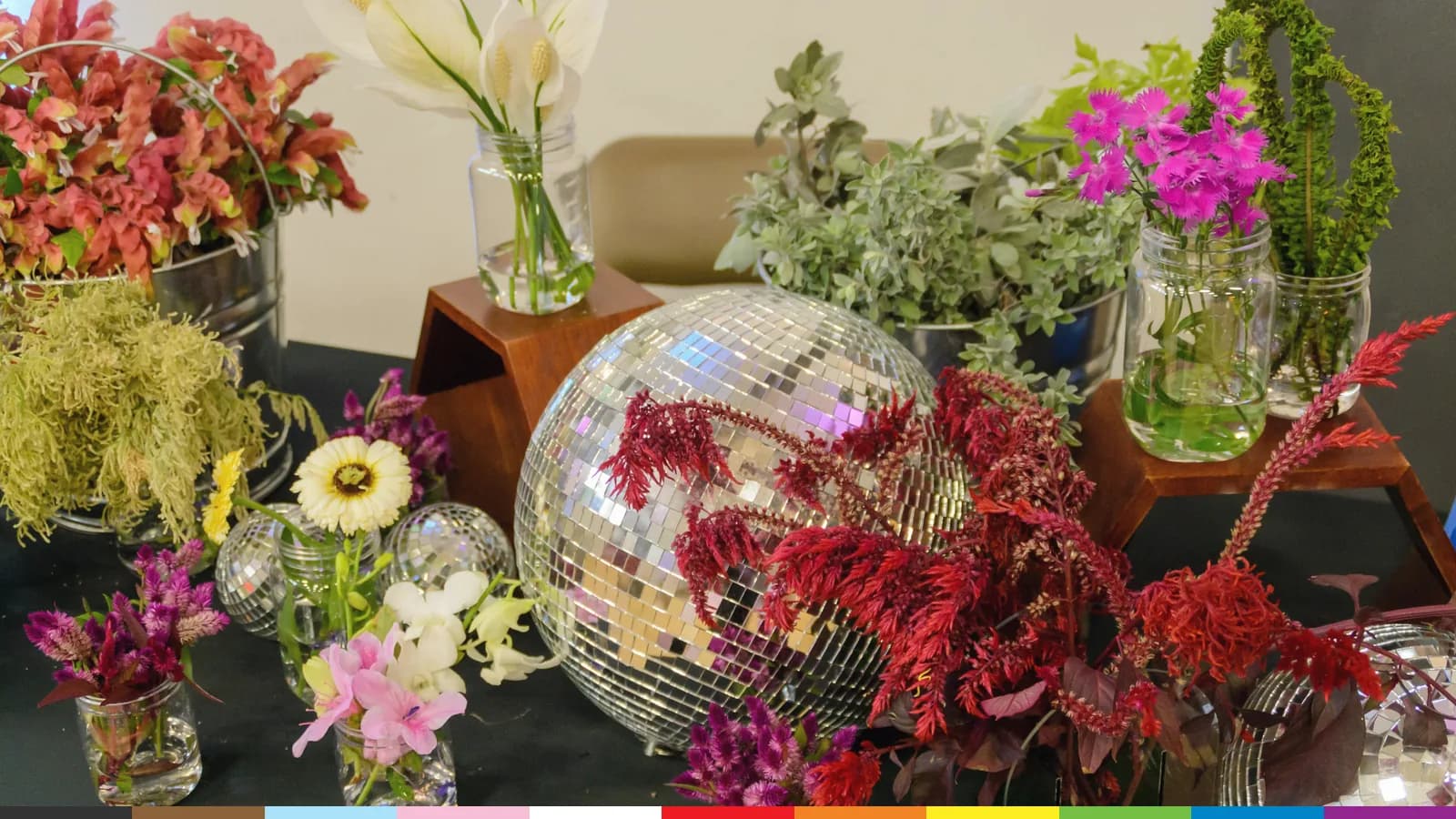 Prom 2023 table decor: bright flowers in glass vases around a mirrored disco ball.