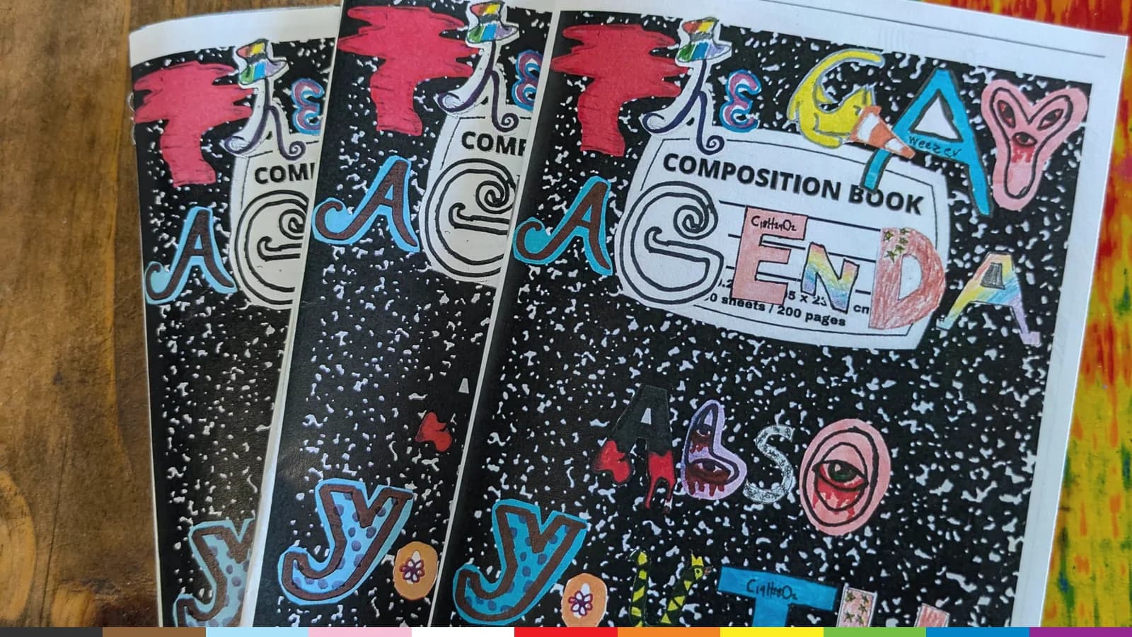 Three composition book zines made at ALSO Youth, covered in bold hand lettering and doodles, on a painted table.