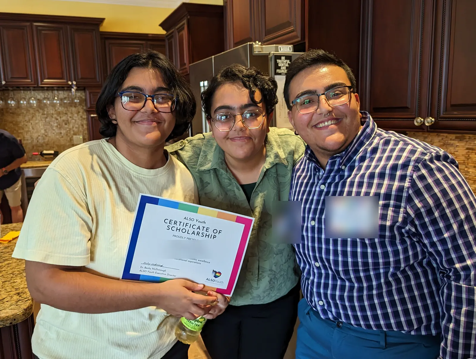 Three smiling young people at an ALSO Youth celebration, one holding a Certificate of Scholarship.